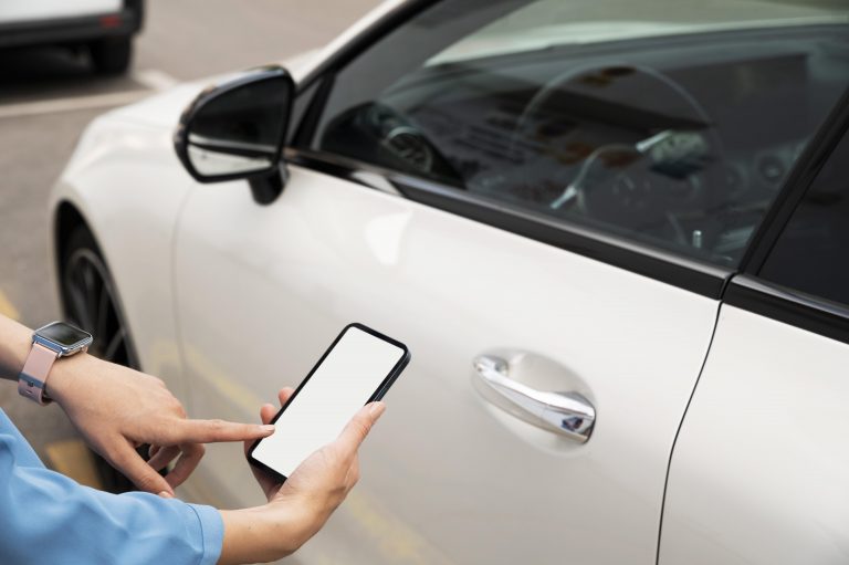 Pessoa utilizando celular ao lado de carro estacionado, representando consulta digital sobre financiamento ou serviços automotivos.